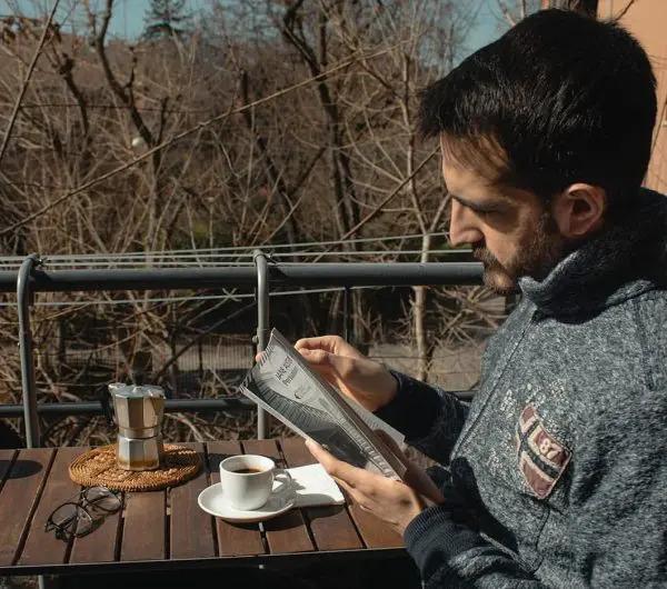 Ruggero Rollini reading outside with a cup of coffee