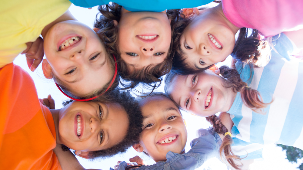 six children in bright shirts smiling