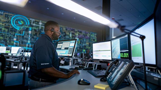 A person with headset looking at multiple monitors in an office setting.