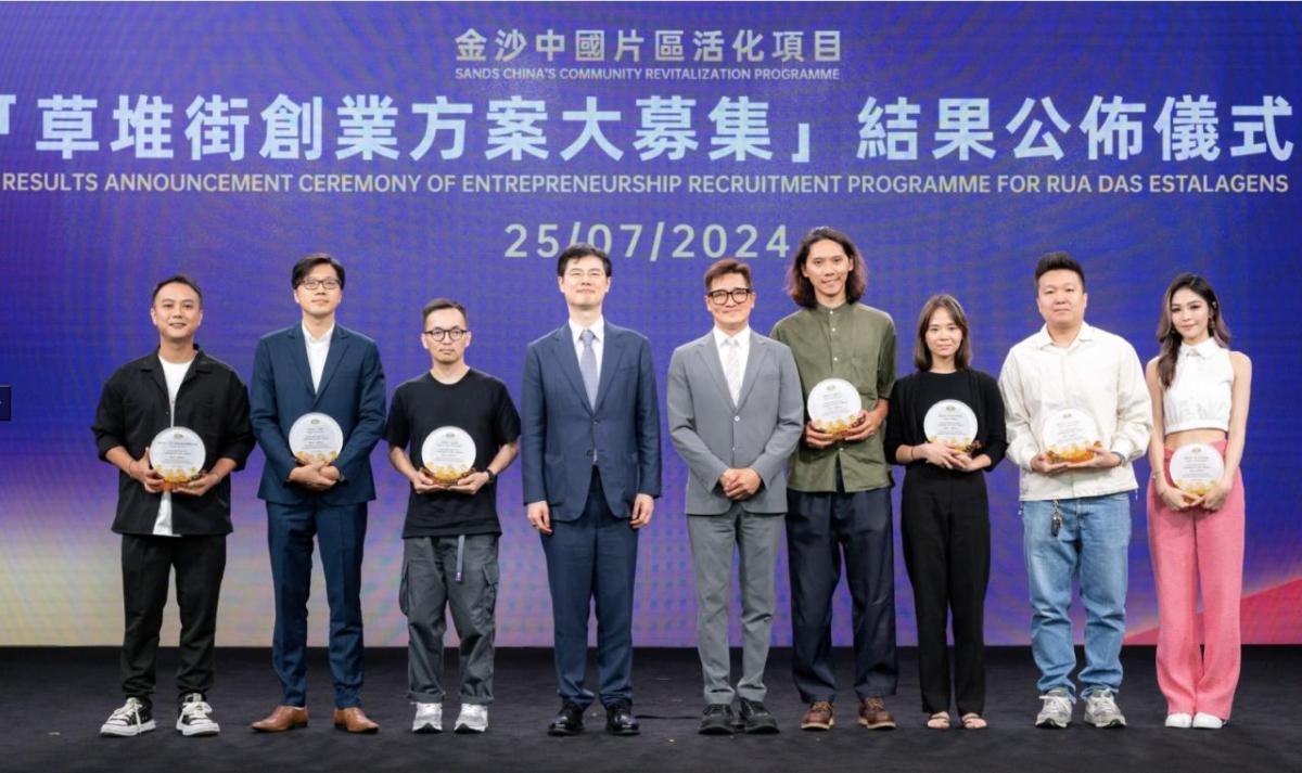 Nine people assembled on stage. Seven are holding awards
