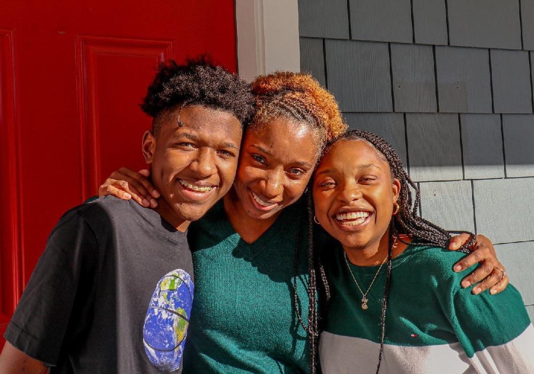 Robin Valentine, graduate of the Compass FSS program with Metro Housing Boston, with her children outside their newly purchased home. mom standing in center of two teen children