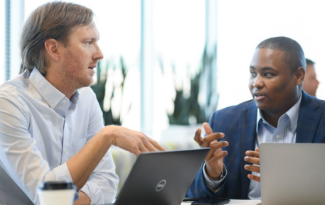 Two people talking while on laptops