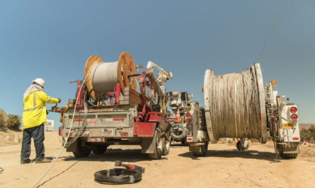 a worker in safety gear and large coils of cable