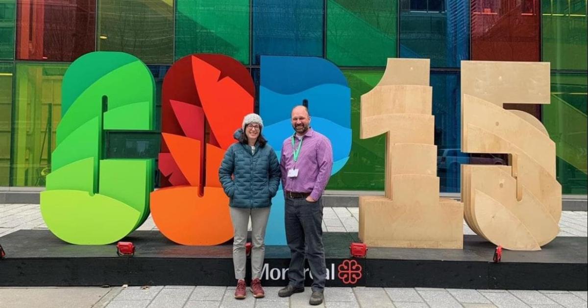 Two people in front of a COP 15 sign