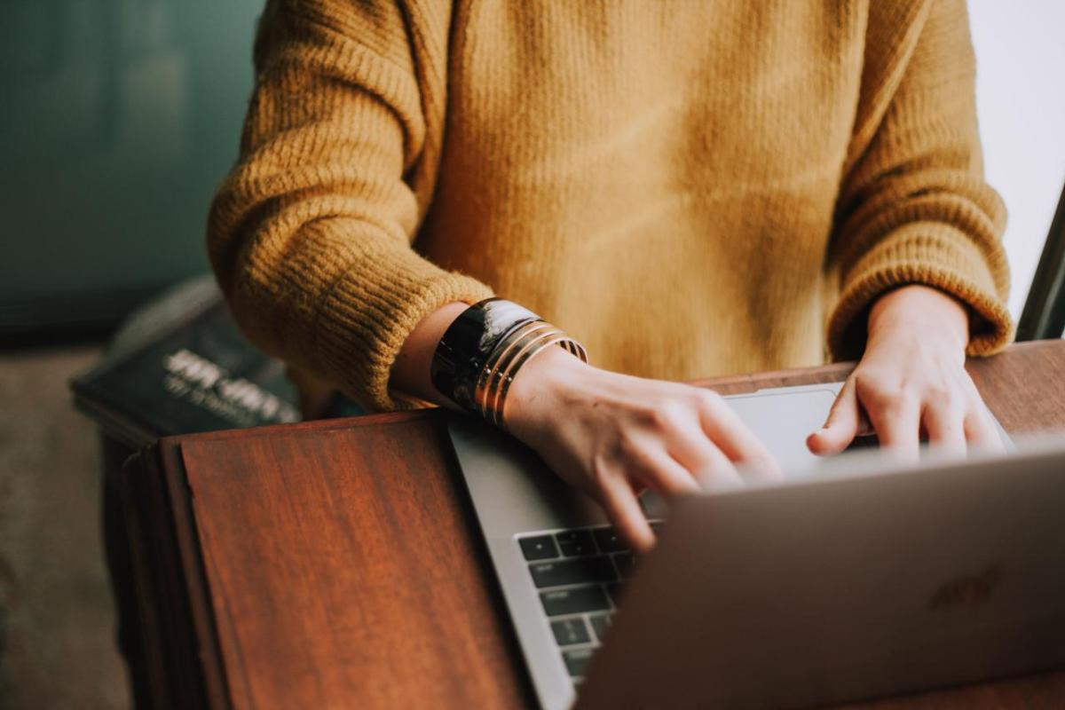 A person typing on a laptop computer at a desk.