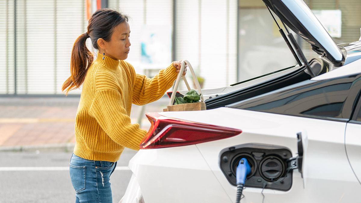 person putting groceries into a charging car