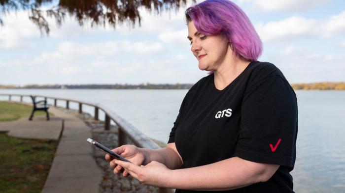 Crystal Morris looking at a phone beside a river