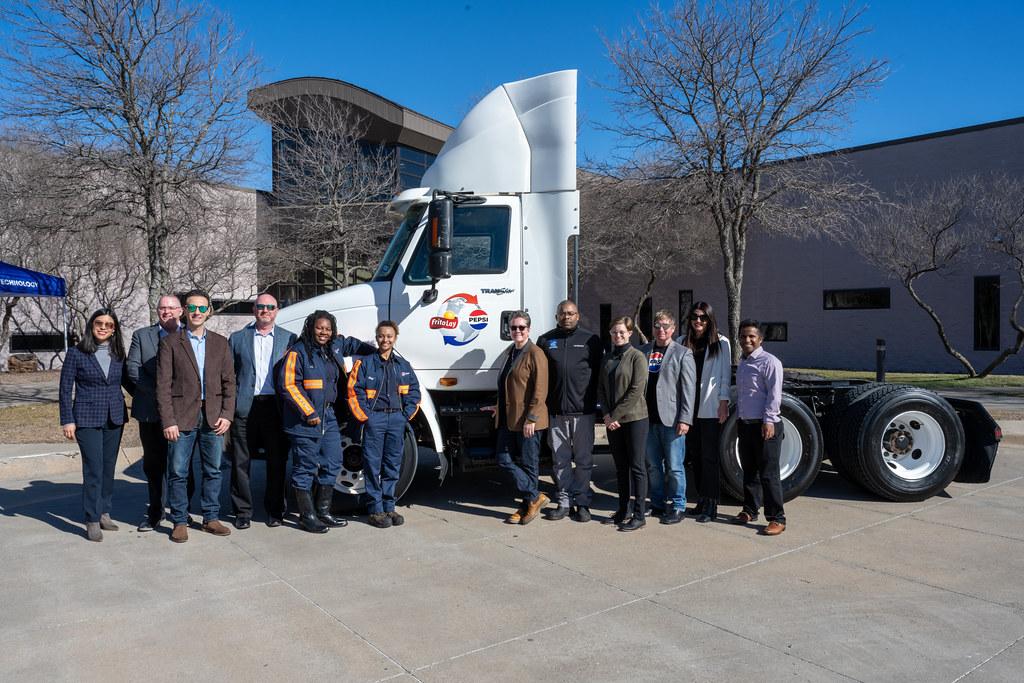 A group of people posed outside in front of a semi truck.