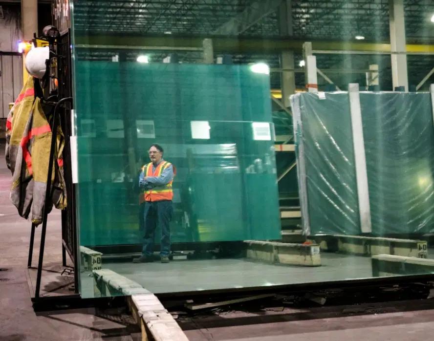 Dean standing by large sheets of glass.