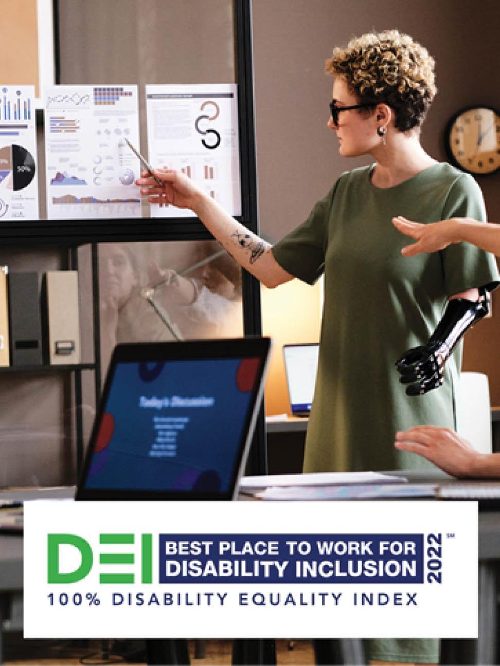 a person with a prosthetic left arm standing, pointing at a posted graph. Another sitting at a close table gesturing. "DEI Best place to work for disability inclusion 2022, 100% disability equality index" at the bottom