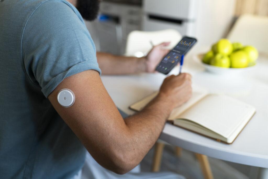 Diabetic man checking glucose patch sensor.