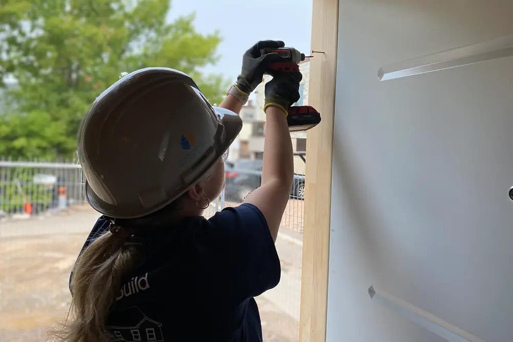 A person using a drill on a door frame.