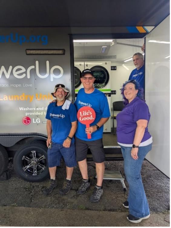 People smiling outside a ShowerUp mobile laundry unit