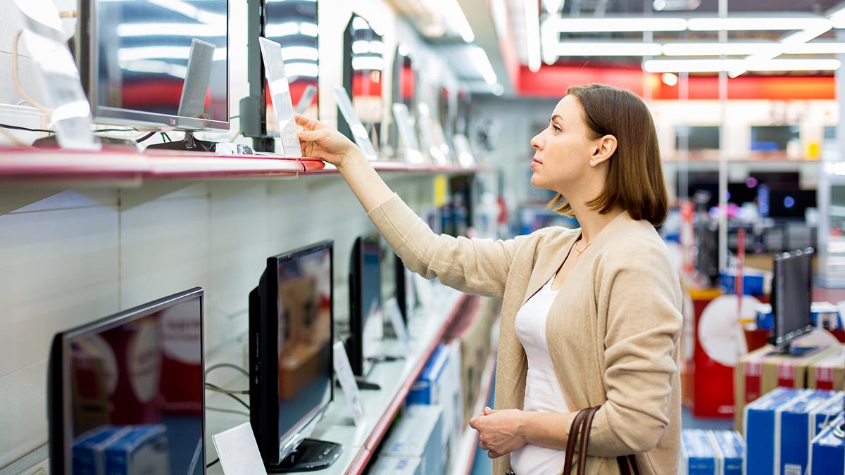 A person is a shop looking at technology products on a shelf 