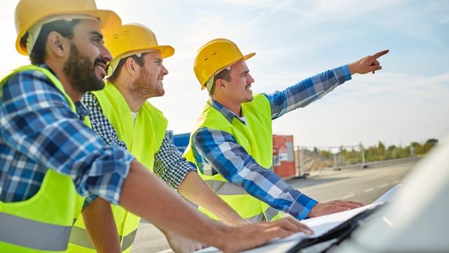 Workers wearing hard hats pointing into the distance