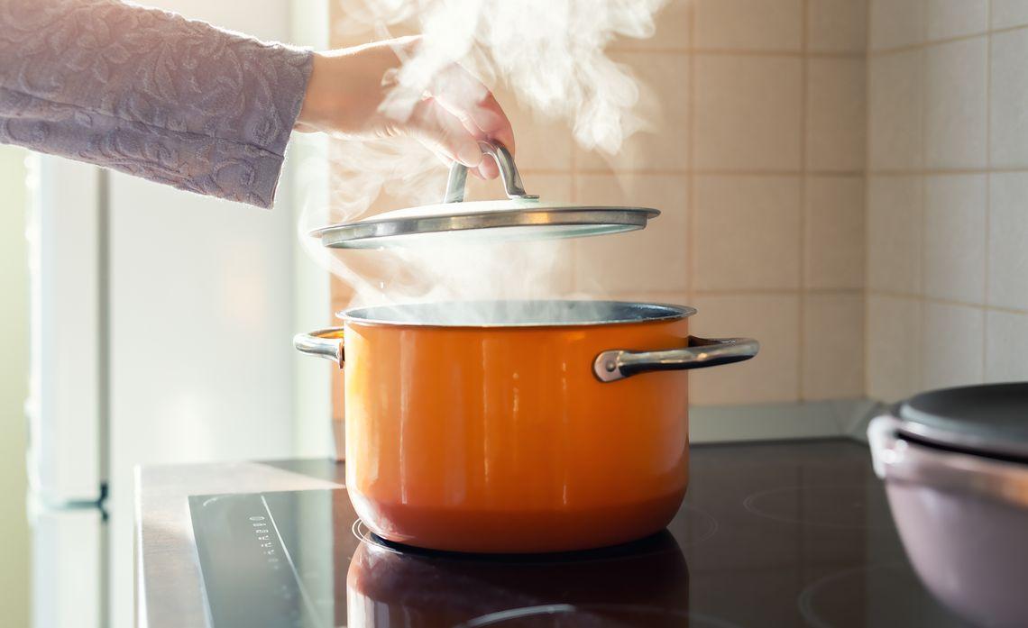 Steam rising from an orange pot on an electric range