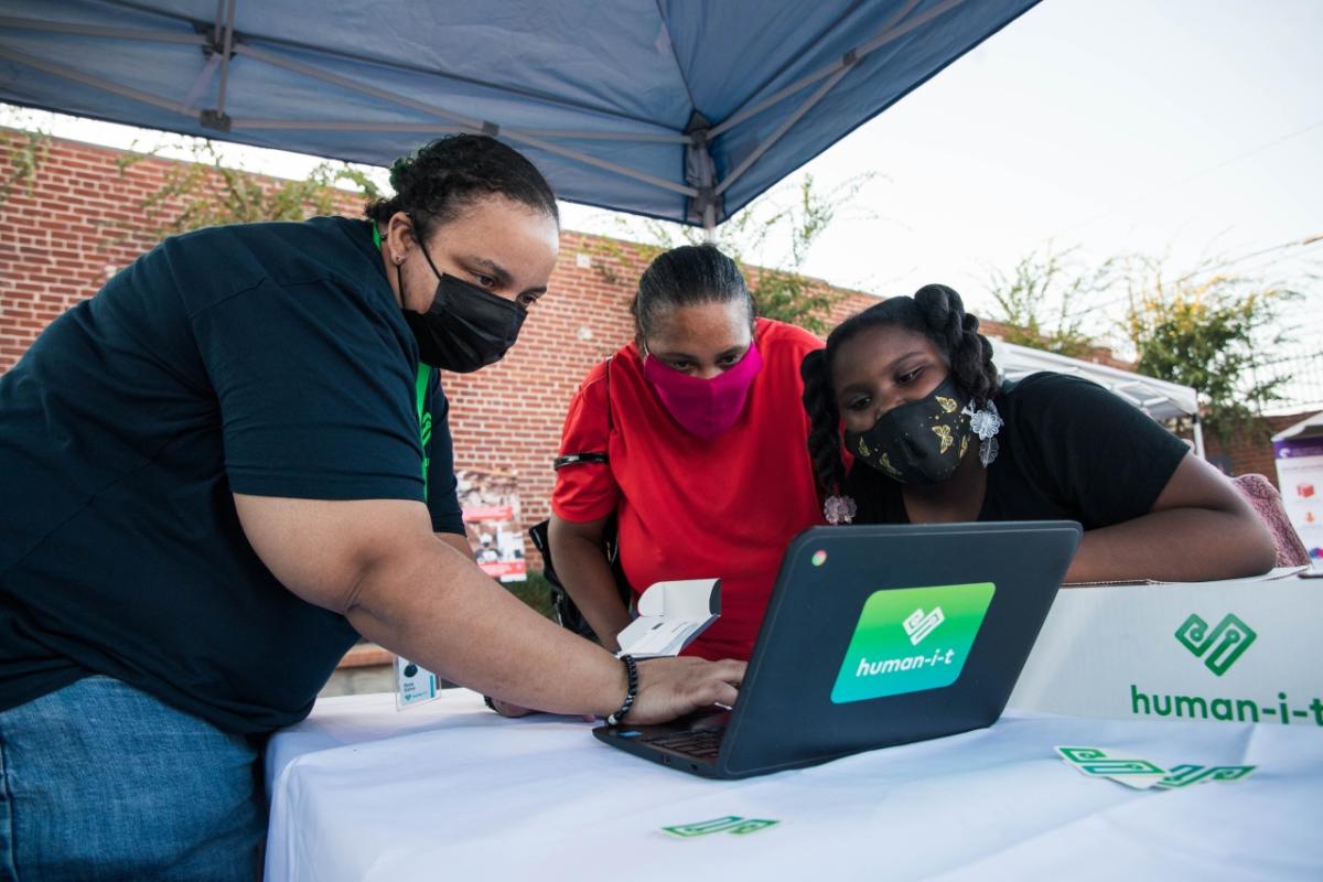 Three people looking at a Human-I-T laptop