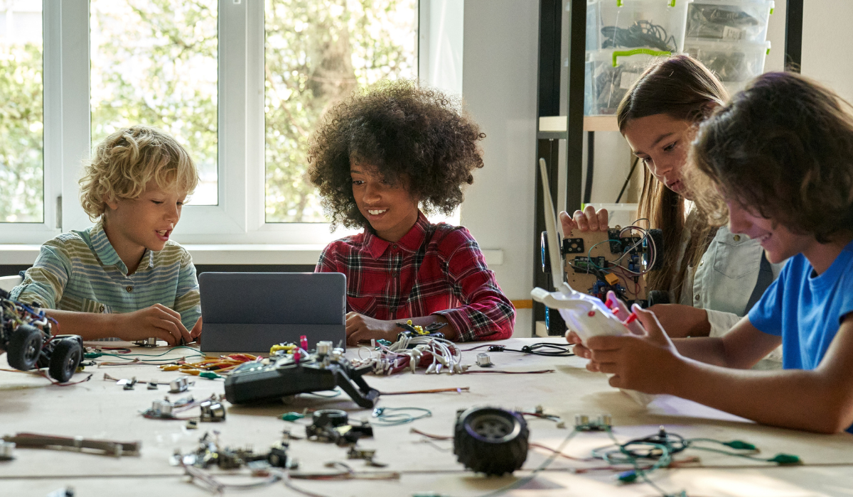 Four children sat around a table using technology 