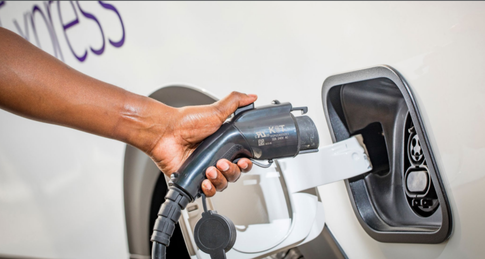 a hand holding a vehicle charge plug near the port on the vehicle