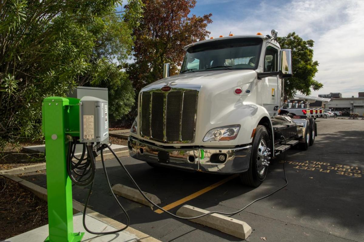 An electric semi-truck parked and plugged into a charging station.