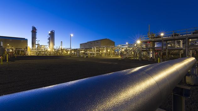 A long pipe in an industrial plant. Sun barely rising in the corner.