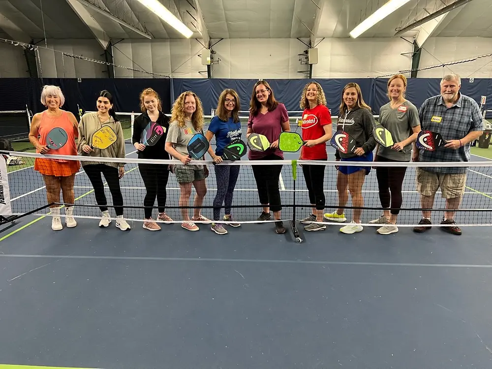 A group of women holding pickle ball paddles