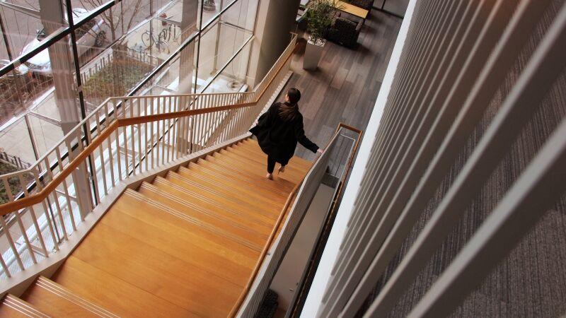 Image courtesy of Thomson Reuters A person walking down a long, wooden, staircase.