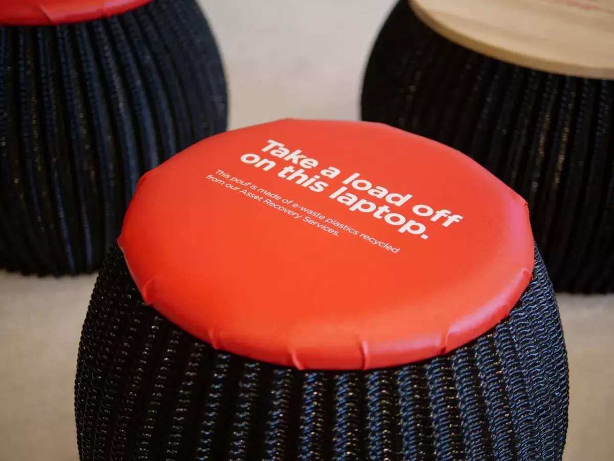 A black stool with Orange cushion "Take a load off on this laptop." printed on top.