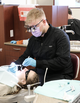 A dental student examines a patient's teeth.