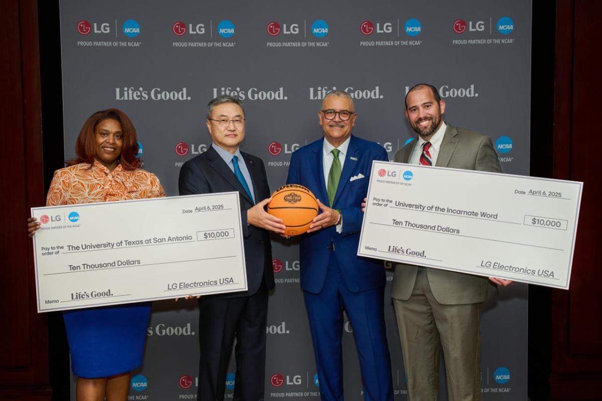 Four people posing with two oversized checks and a basketball