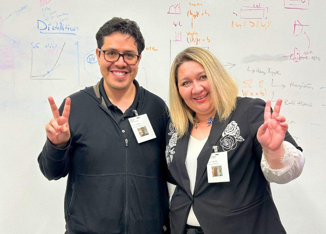Two people standing together, making peace sign gestures