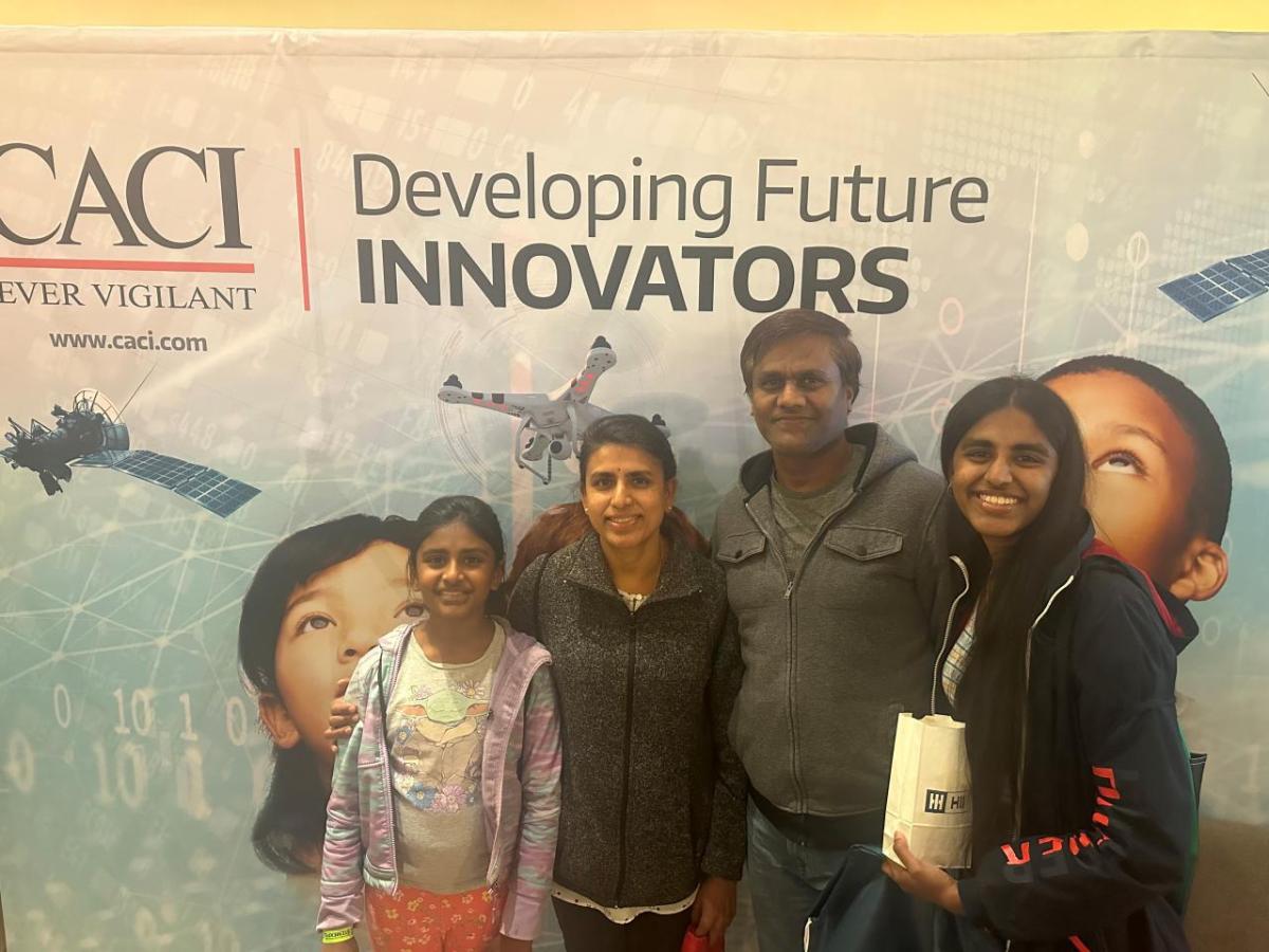 A family group posed in front of a CACI banner