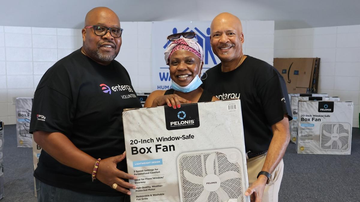 3 people holding a box fan