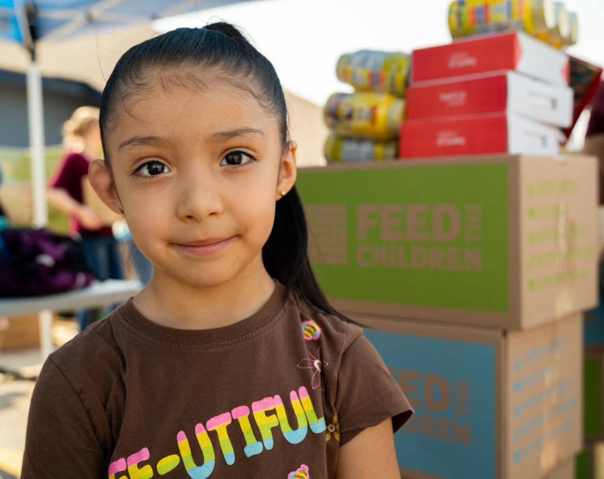 Child with boxes of food stacked behind her