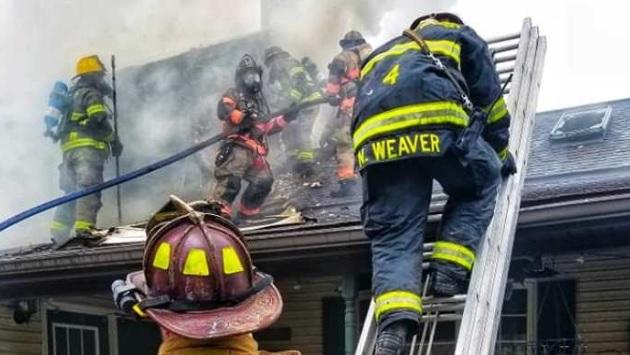 Firefighters climbing onto smoking roof