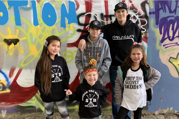 An adult and four children in front of a wall mural