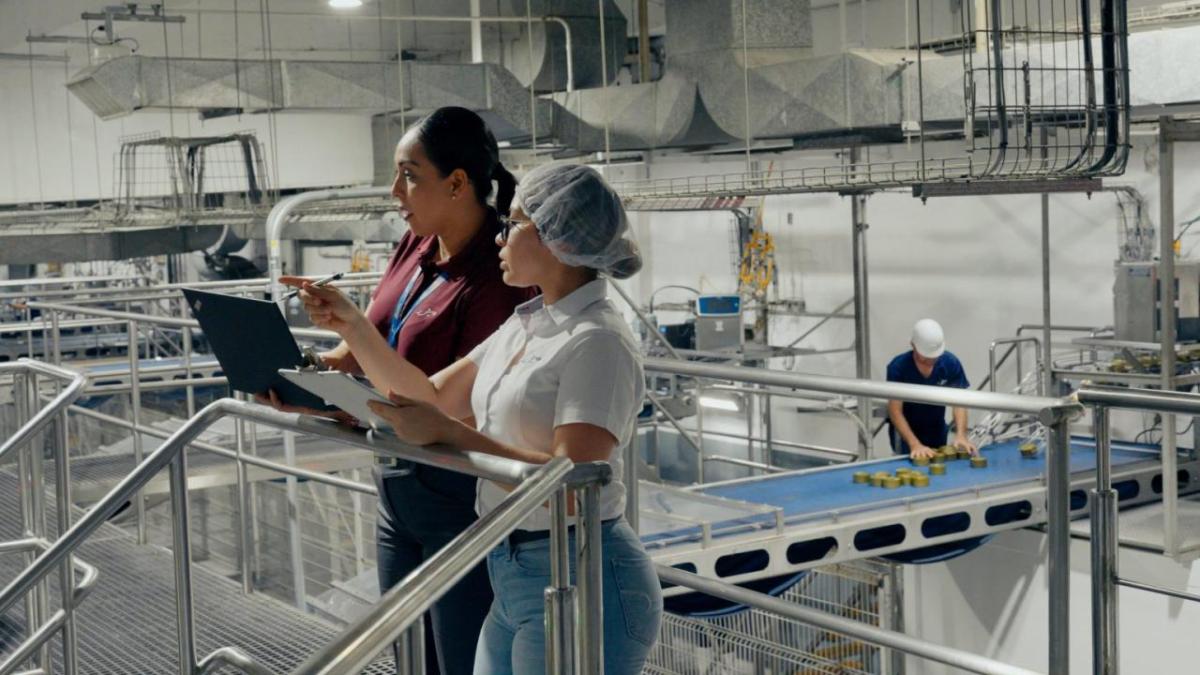 Two people looking at a laptop in an industrial plant.