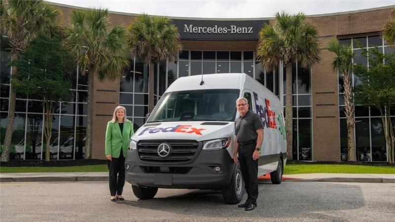 Two people standing beside a FedEx van