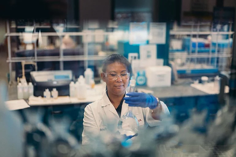 A scientist holding a glass container