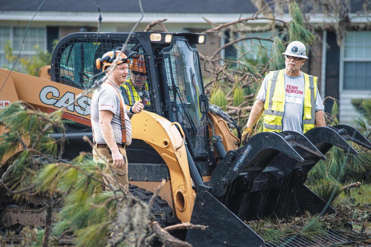 CASE Construction Equipment, a brand of CNH, is providing essential support in the wake of Hurricane Helene and Milton’s devastating impact to the southeastern region of the U.S. People standing next to a scooping types construction vehicle. Debris and branches surrounding.
