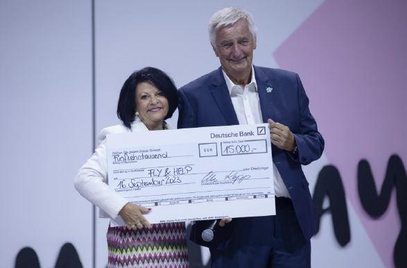 Two people posing with a large check made to Fly & Help.