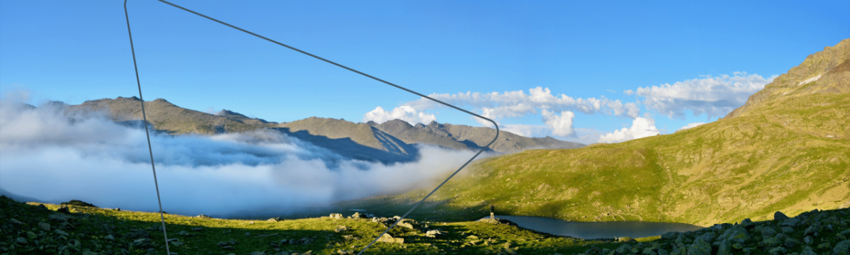 Panoramic view of hills and fog running through the valleys. A blue sky above with very few clouds.