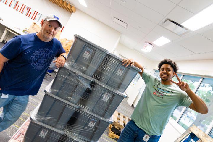 Two volunteers next to large boxes