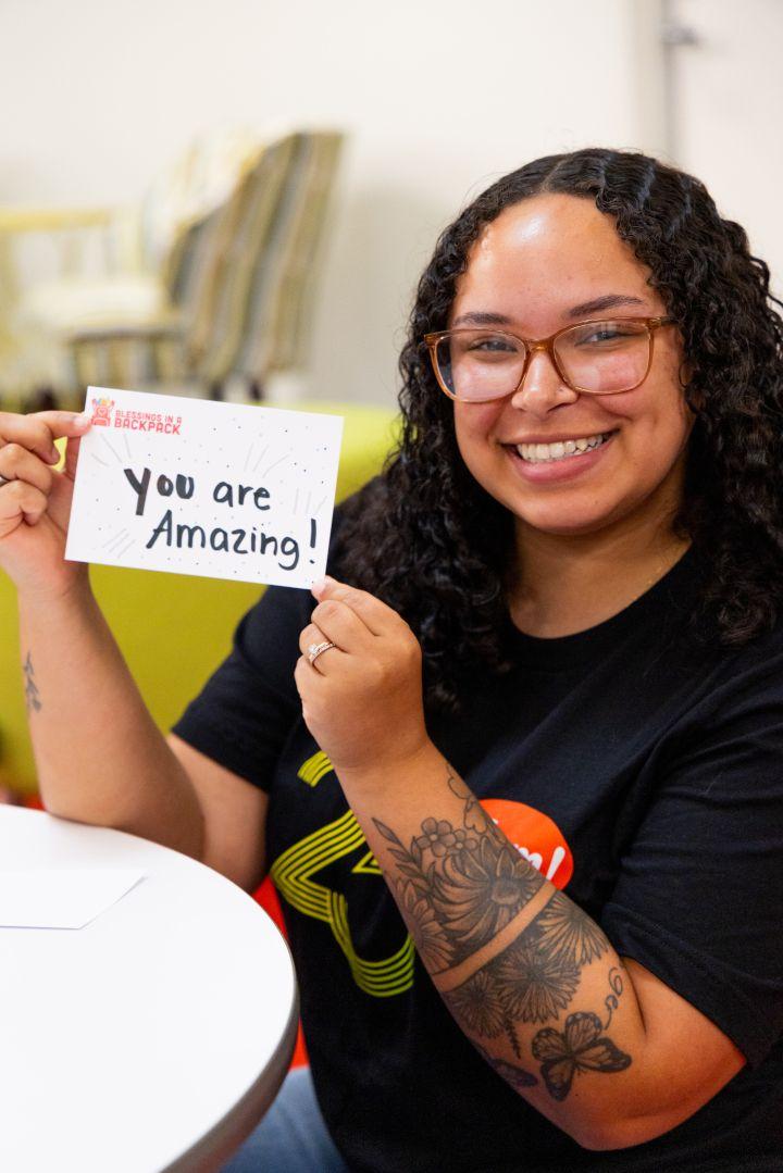 Volunteer holding sign reading "you are amazing!"