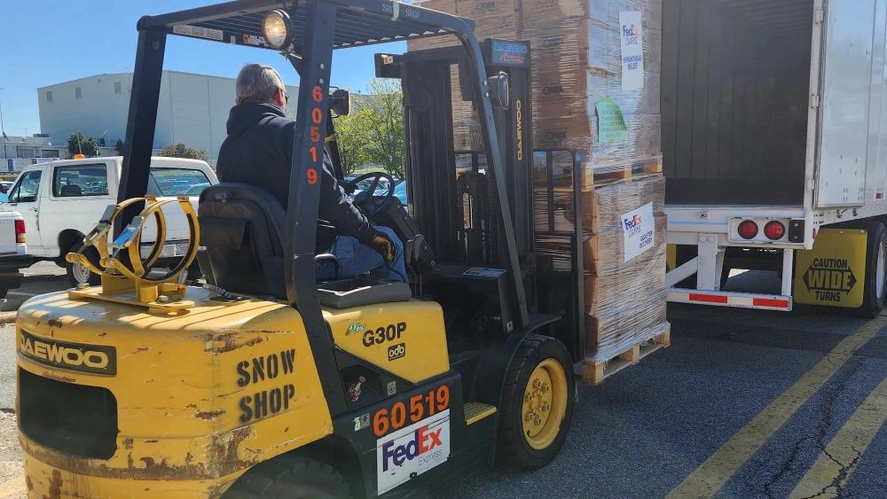 a person loads an open trailer using a forklift