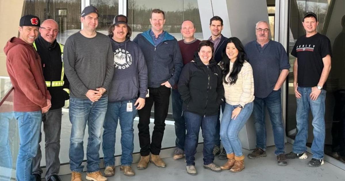 A team of people in a group pose outside a building.