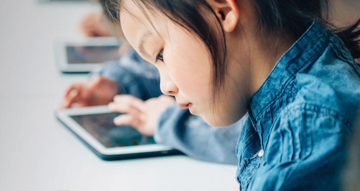 Young child reading off a tablet