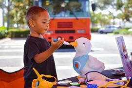 Gabe using a toy syringe to feed his Aflac stuffed duck