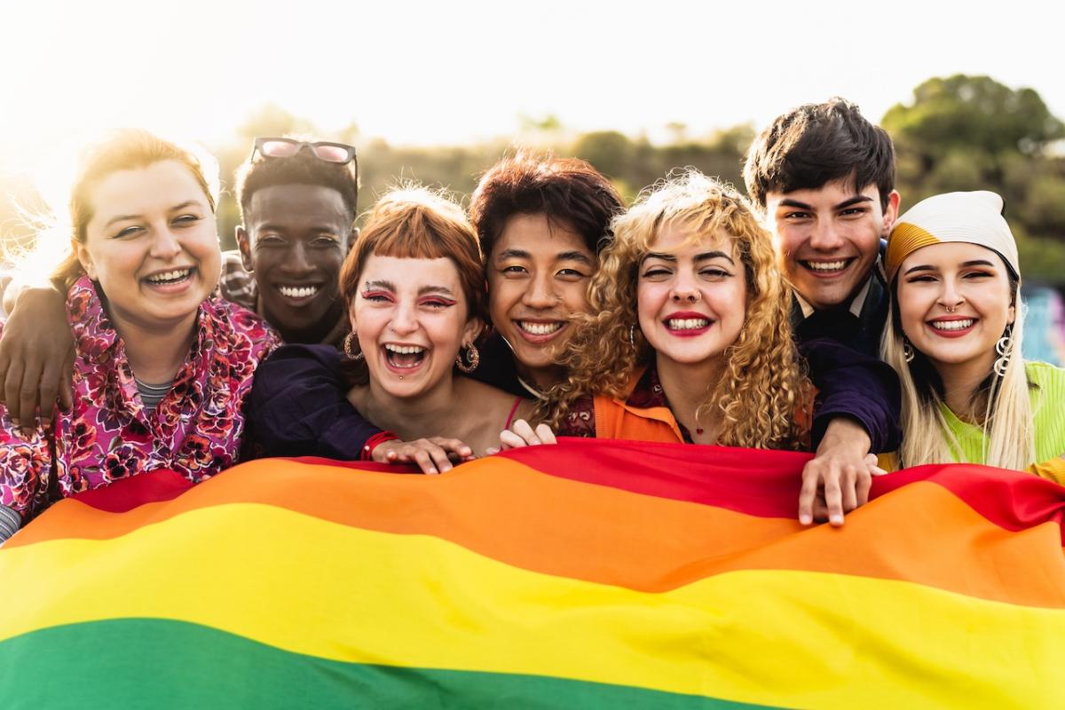 Group of individuals holding a rainbow flag.