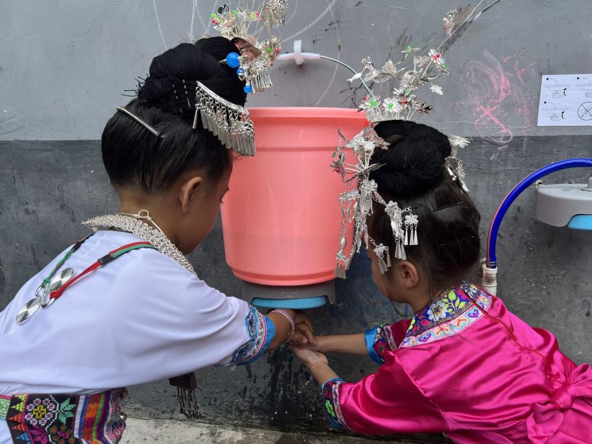 girls in traditional dress washing their hands